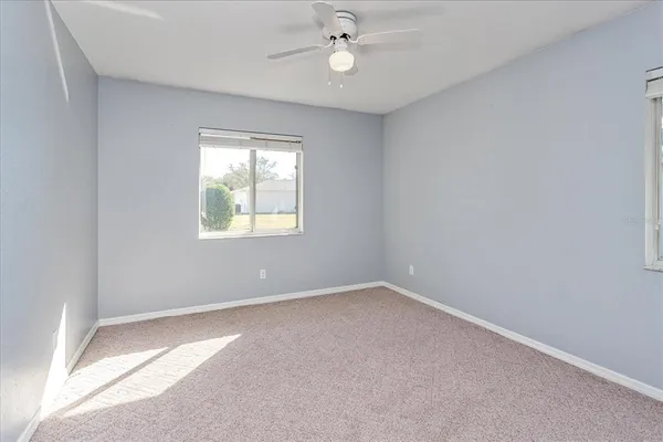 an empty room with windows and ceiling fan