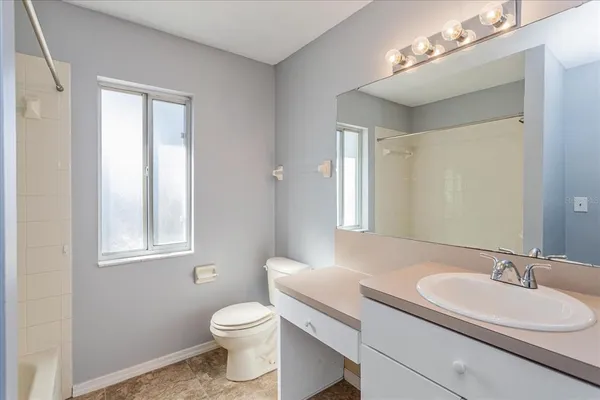 a bathroom with a toilet a sink a mirror a window and vanity