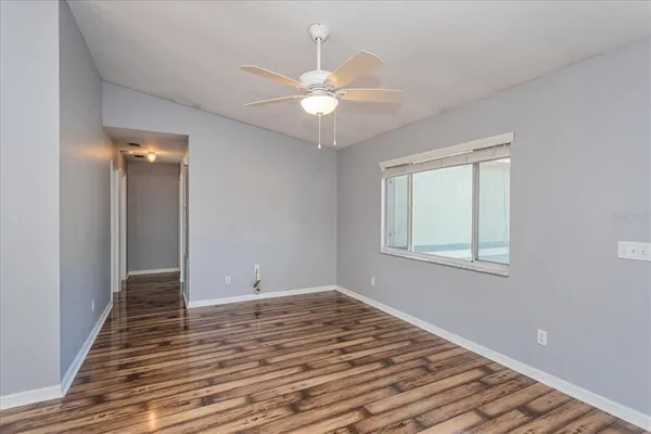 a view of an empty room with wooden floor and a window