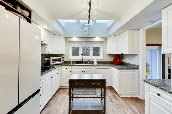 a kitchen with stainless steel appliances granite countertop a stove cabinets and wooden floor