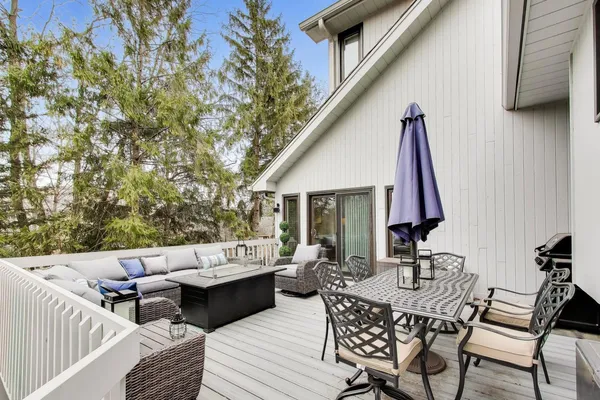 a view of a patio with couches table and chairs with wooden floor and fence