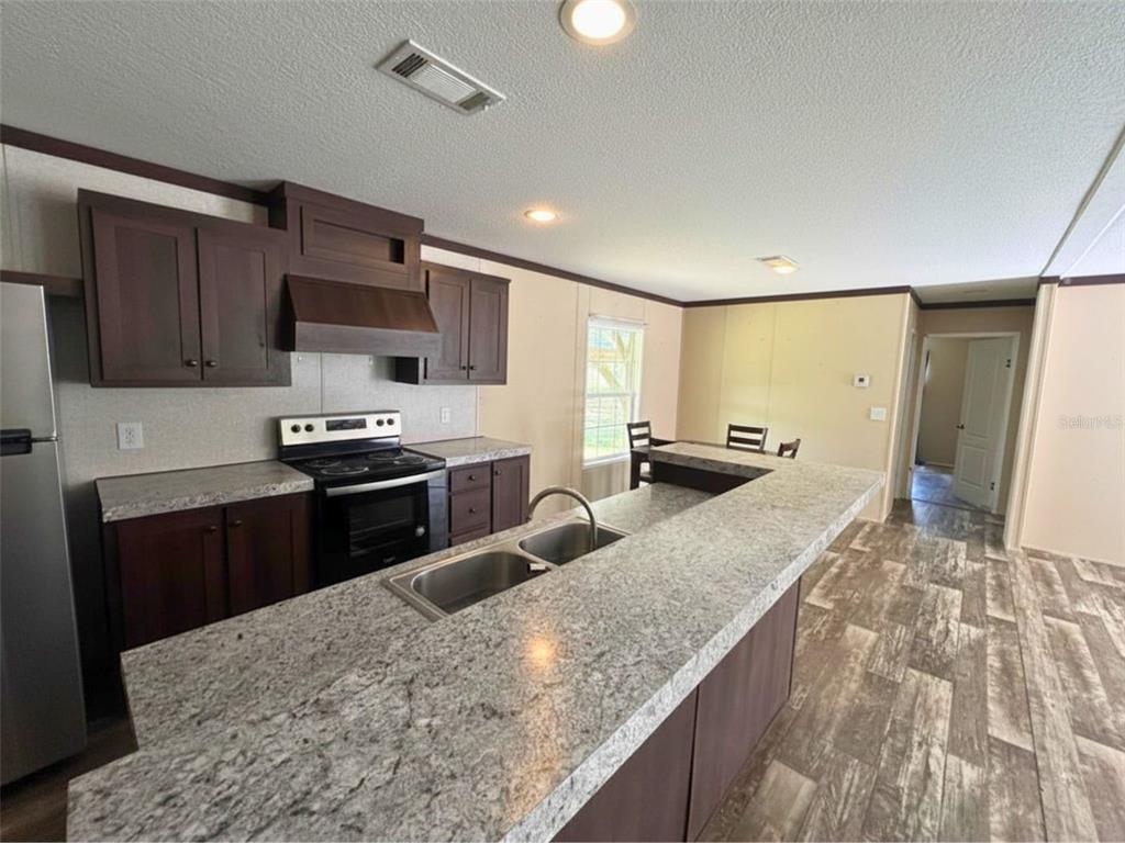 9827 Southeast Hoth Road Arcadia, FL 34266 - Photo 14 of 28 a kitchen with stainless steel appliances granite countertop a sink refrigerator and microwave