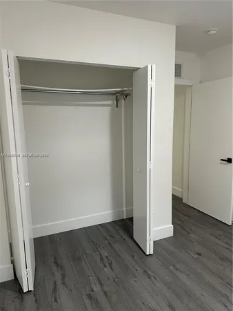 an empty room with wooden floor and closet