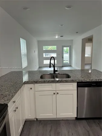 a kitchen with granite countertop a sink and cabinets