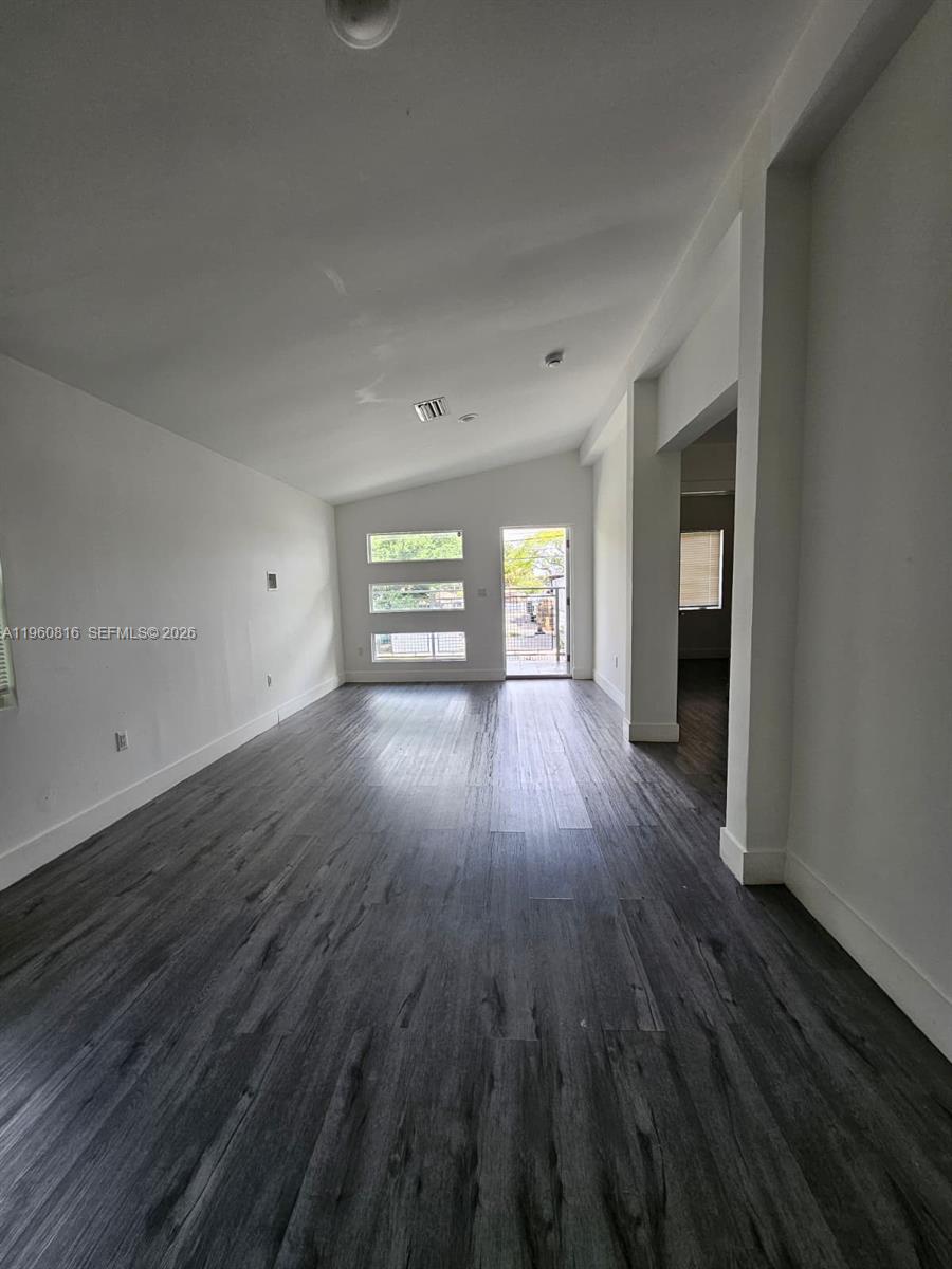 224 Northwest 57th Street, Unit B Miami, FL 33127 - Photo 33 of 40 an empty room with wooden floor and windows