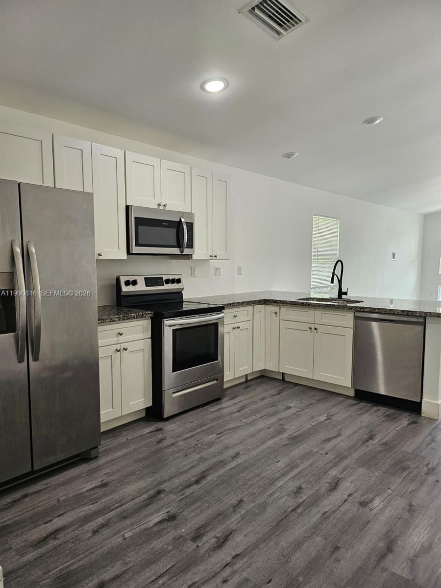 224 Northwest 57th Street, Unit B Miami, FL 33127 - Photo 36 of 40 a kitchen with wooden cabinets and stainless steel appliances