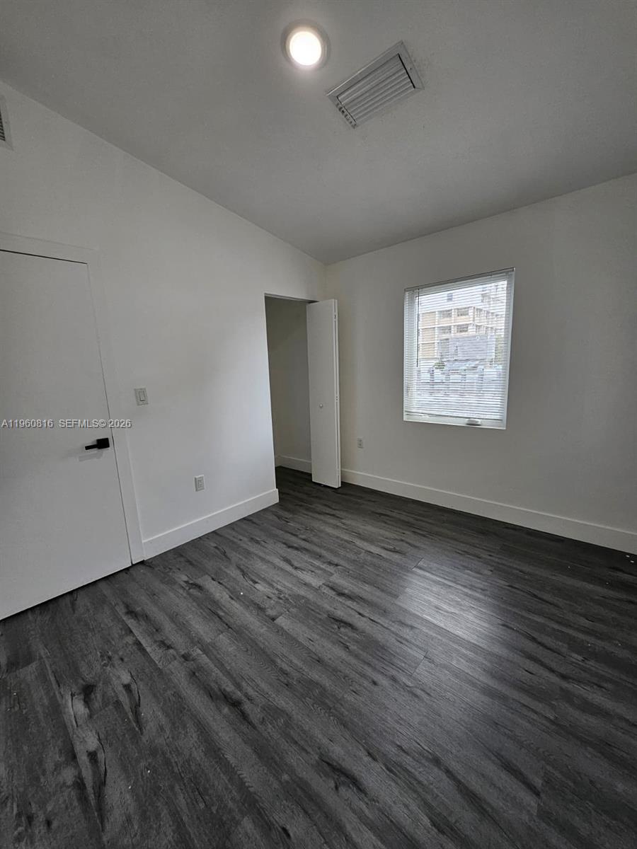 224 Northwest 57th Street, Unit B Miami, FL 33127 - Photo 37 of 40 an empty room with wooden floor and windows
