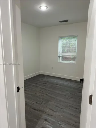 an empty room with wooden floor and window