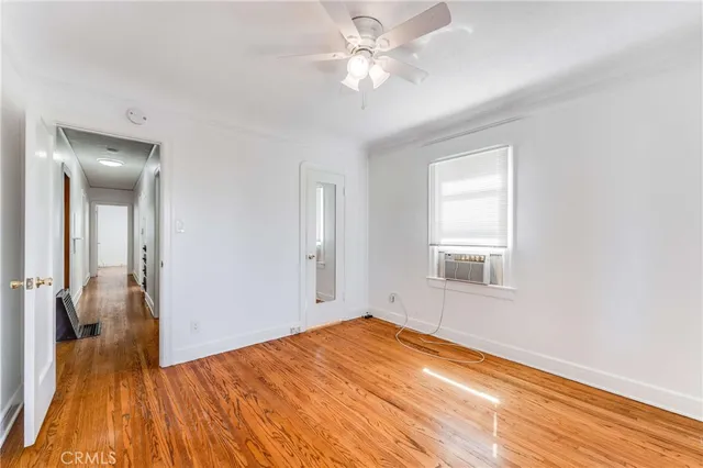 a view of empty room with wooden floor and fan