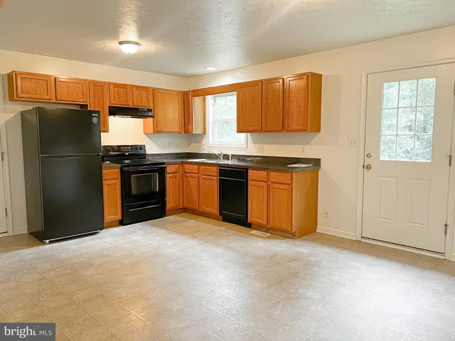 a kitchen with stainless steel appliances granite countertop a stove top oven a refrigerator and a sink