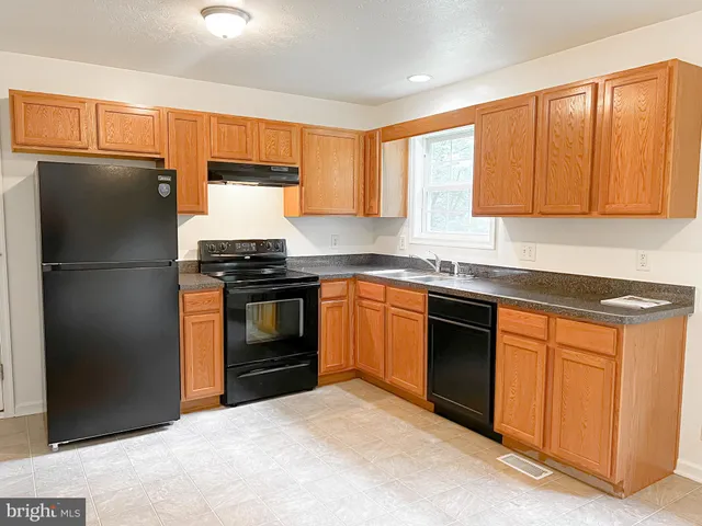 a kitchen with granite countertop a refrigerator stove and sink