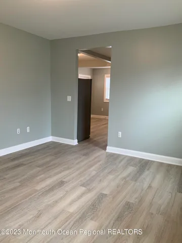 a view of an empty room with wooden floor and closet