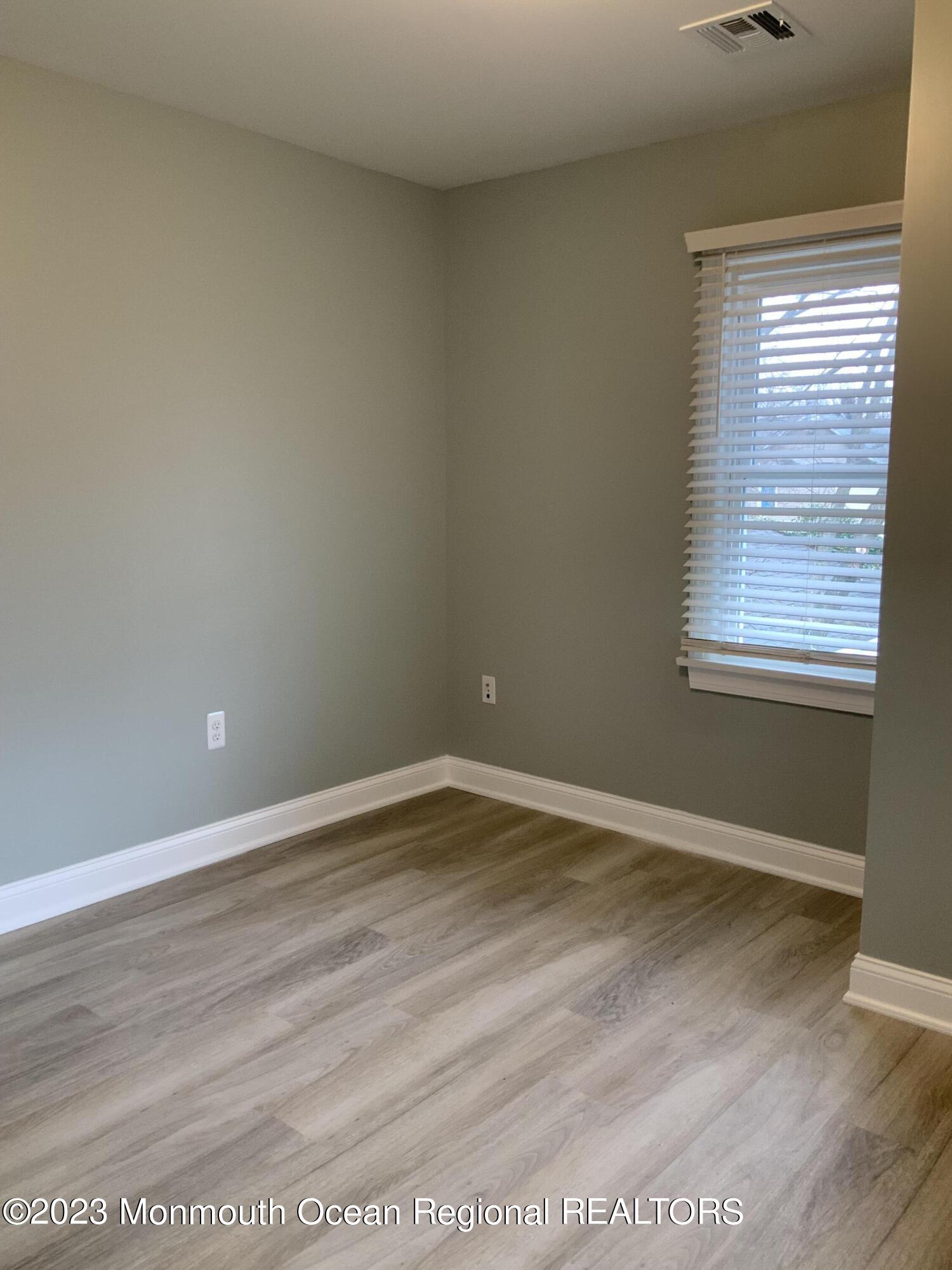 104 Bridge Avenue, Unit APARTMENT 1 Red Bank, NJ 07701 - Photo 23 of 25 an empty room with wooden floor and windows