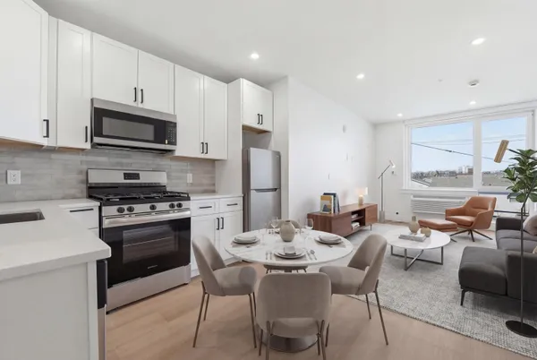 a kitchen with stainless steel appliances a stove a sink a microwave a refrigerator a stove a dining table and chairs