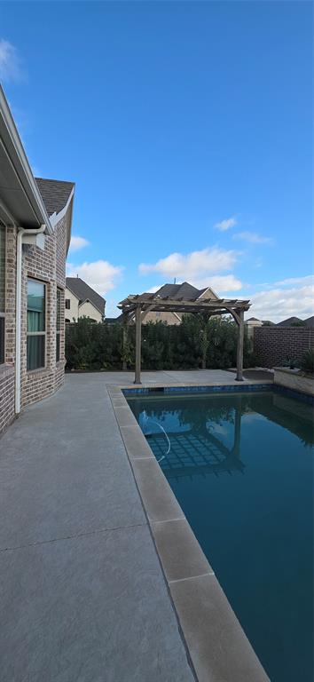 2000 Johnson Road Mansfield, TX 76063 - Photo 20 of 27 Brick exterior, in-ground swimming pool, concrete patio, wooden pergola, and privacy landscaping