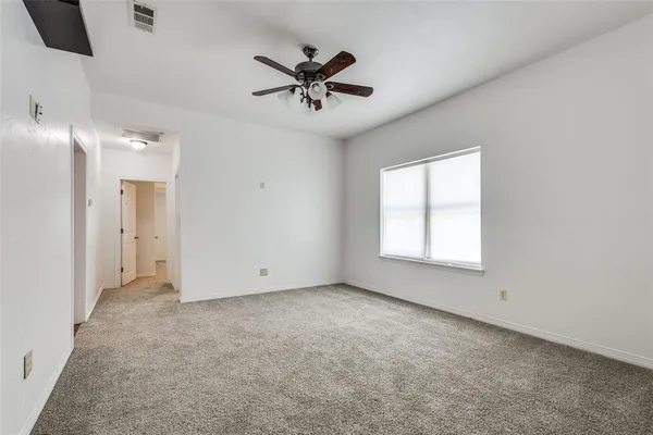an empty room with fan and windows