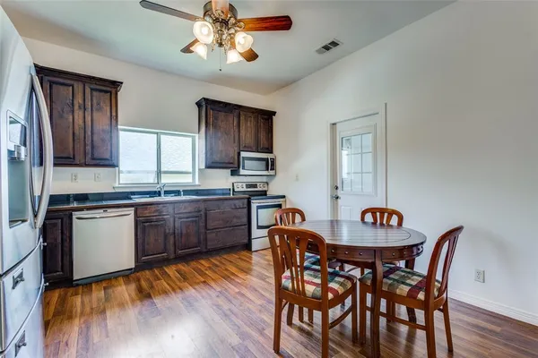 a kitchen with stainless steel appliances granite countertop a kitchen island hardwood floor sink stove dining table and chairs