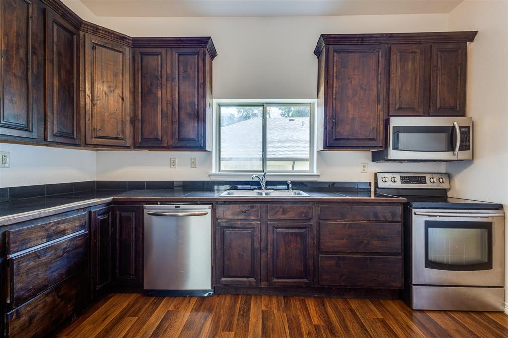 618 East Woodard Street Denison, TX 75021 - Photo 9 of 22 a kitchen with stainless steel appliances granite countertop wooden cabinets a stove and a sink