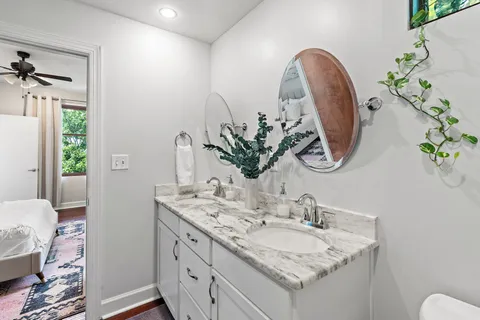 a bathroom with a granite countertop sink a mirror and a potted plant