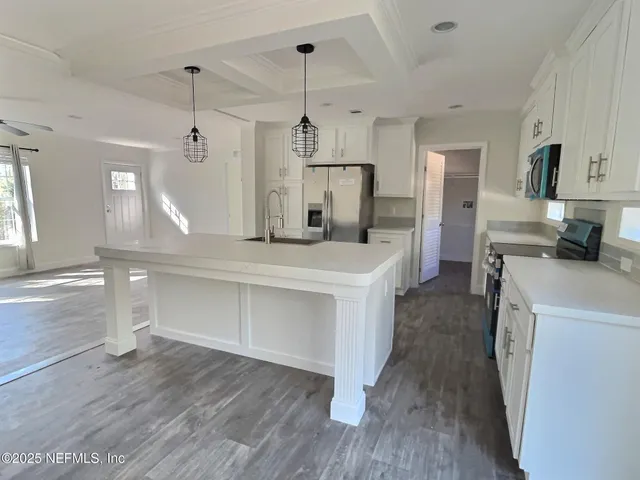 a kitchen with kitchen island white cabinets and stainless steel appliances