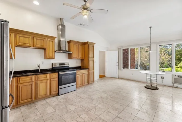 a large kitchen with kitchen island a large counter space a sink stainless steel appliances and cabinets