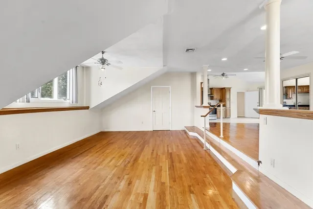 a view of a kitchen with kitchen island a sink wooden floor and a large window