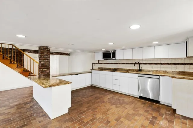 a large white kitchen with stainless steel appliances granite countertop a stove and a sink