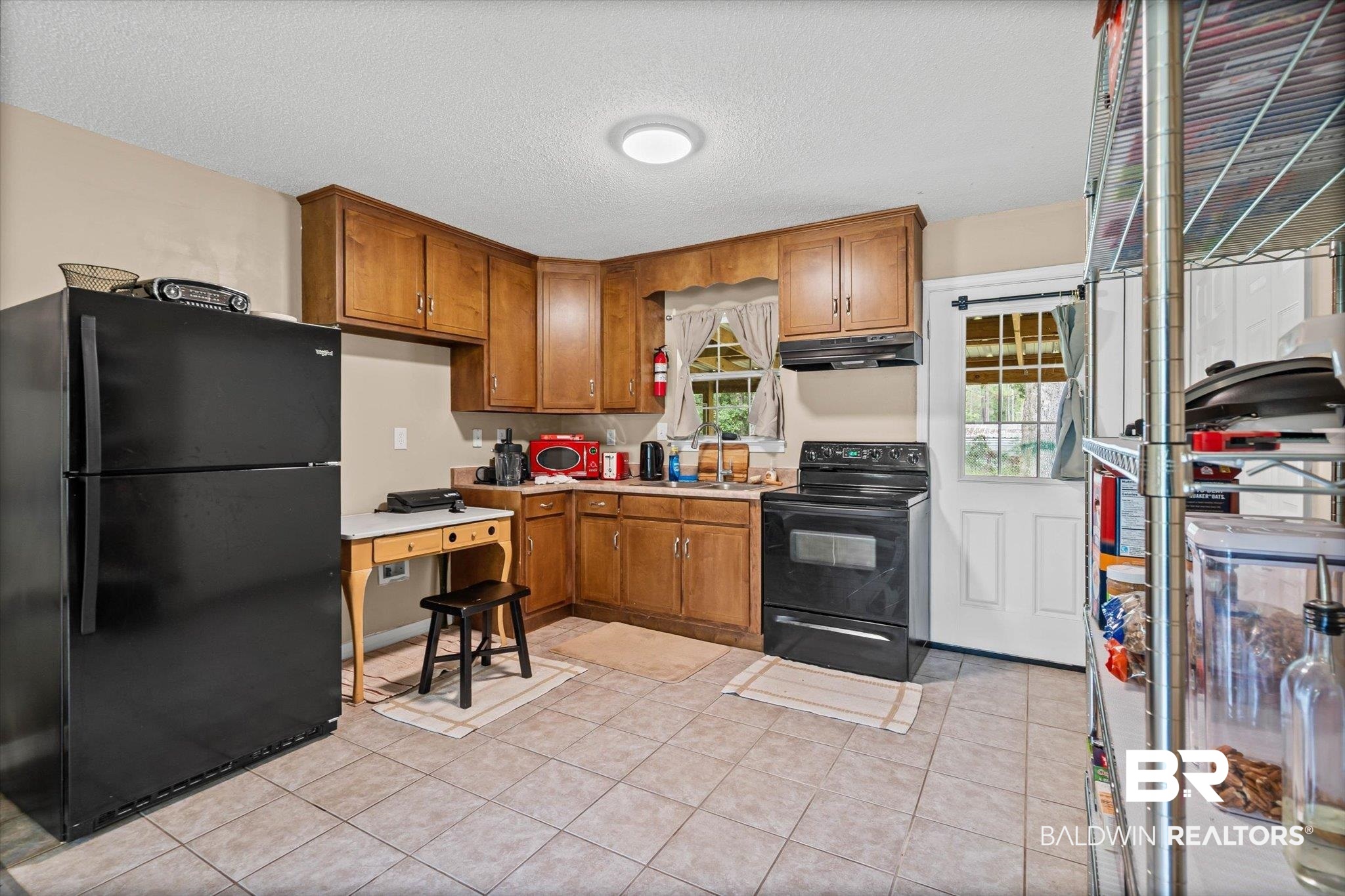 14165 River Oaks Road, Unit A & B Coden, AL 36523 - Photo 4 of 35 Kitchen featuring black appliances, brown cabinetry, a textured ceiling, light countertops, and light tile patterned floors