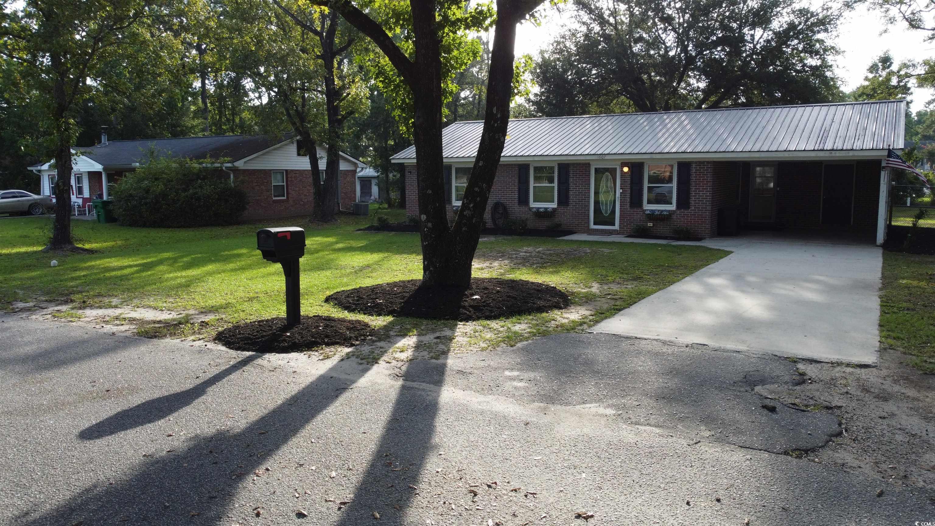 1607 Oak Street Georgetown, SC 29440 - Photo 29 of 31 Ranch-style home with concrete driveway, an attached carport, brick siding, a front lawn, and a metal roof