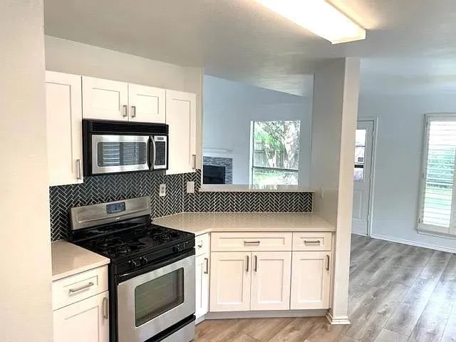 a kitchen with white cabinets and appliances