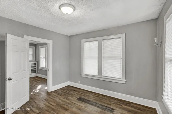 a view of an empty room with wooden floor and a window