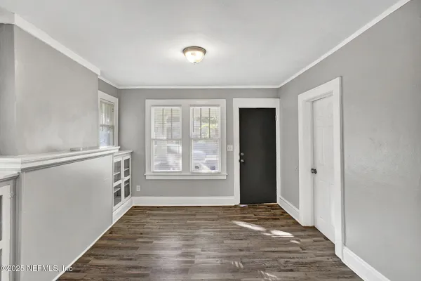 a view of an empty room with a window and wooden floor