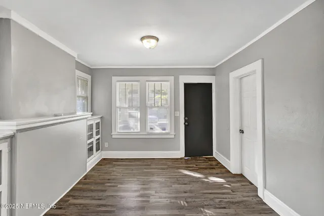 a view of an empty room with a window and wooden floor