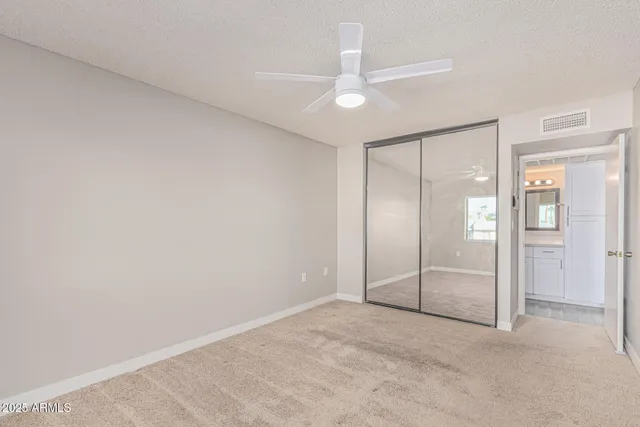 an empty room with windows and ceiling fan