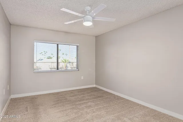 an empty room with a ceiling fan and glass door