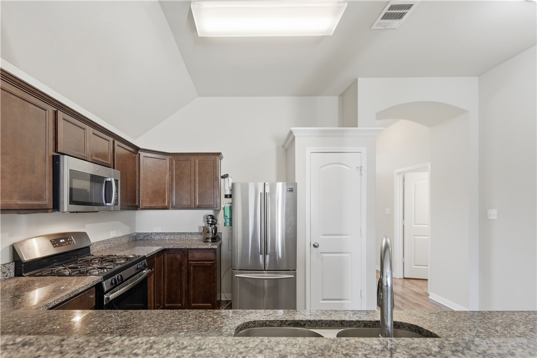 808 Mockingbird Street Navasota, TX 77868 - Photo 8 of 19 a kitchen with granite countertop a refrigerator and a stove top oven