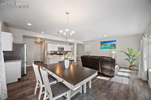 a view of a dining room and livingroom with furniture wooden floor a rug a potted plant and a chandelier