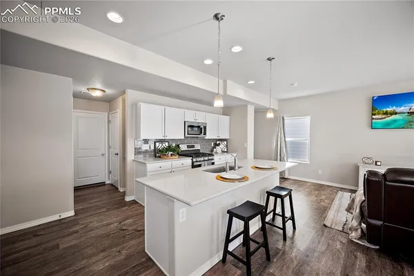 a view of a dining room with furniture a kitchen and chandelier