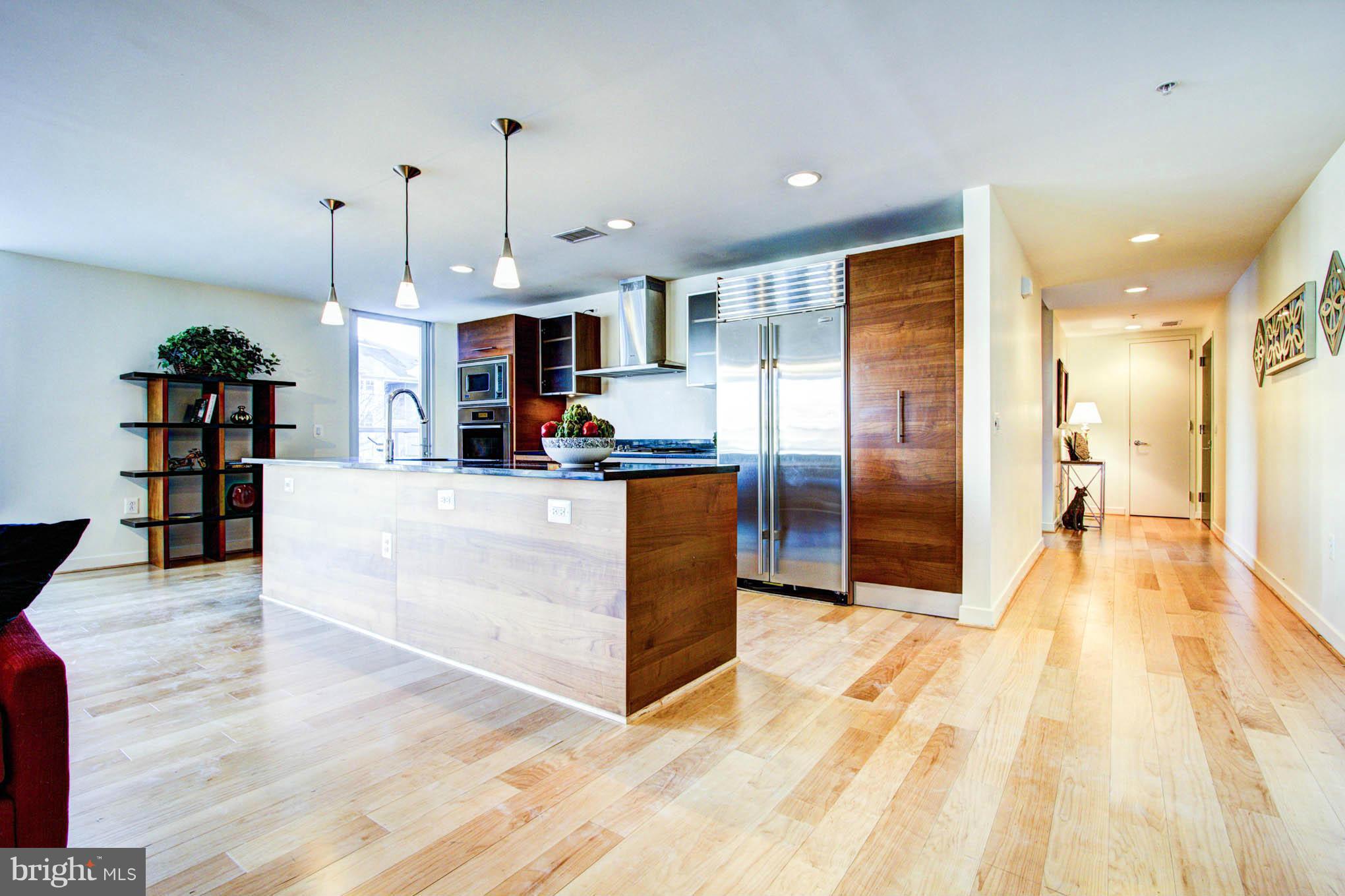 12025 New Dominion Parkway, Unit LL103 Reston, VA 20190 - Photo 12 of 30 a large kitchen with stainless steel appliances kitchen island a large counter top a refrigerator and cabinets