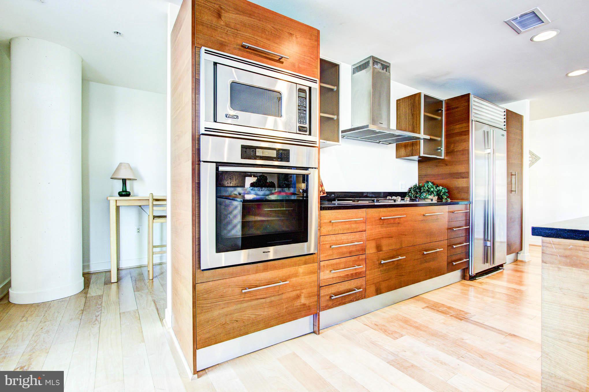 12025 New Dominion Parkway, Unit LL103 Reston, VA 20190 - Photo 16 of 30 a kitchen with stainless steel appliances kitchen island wooden cabinets and a stove top oven
