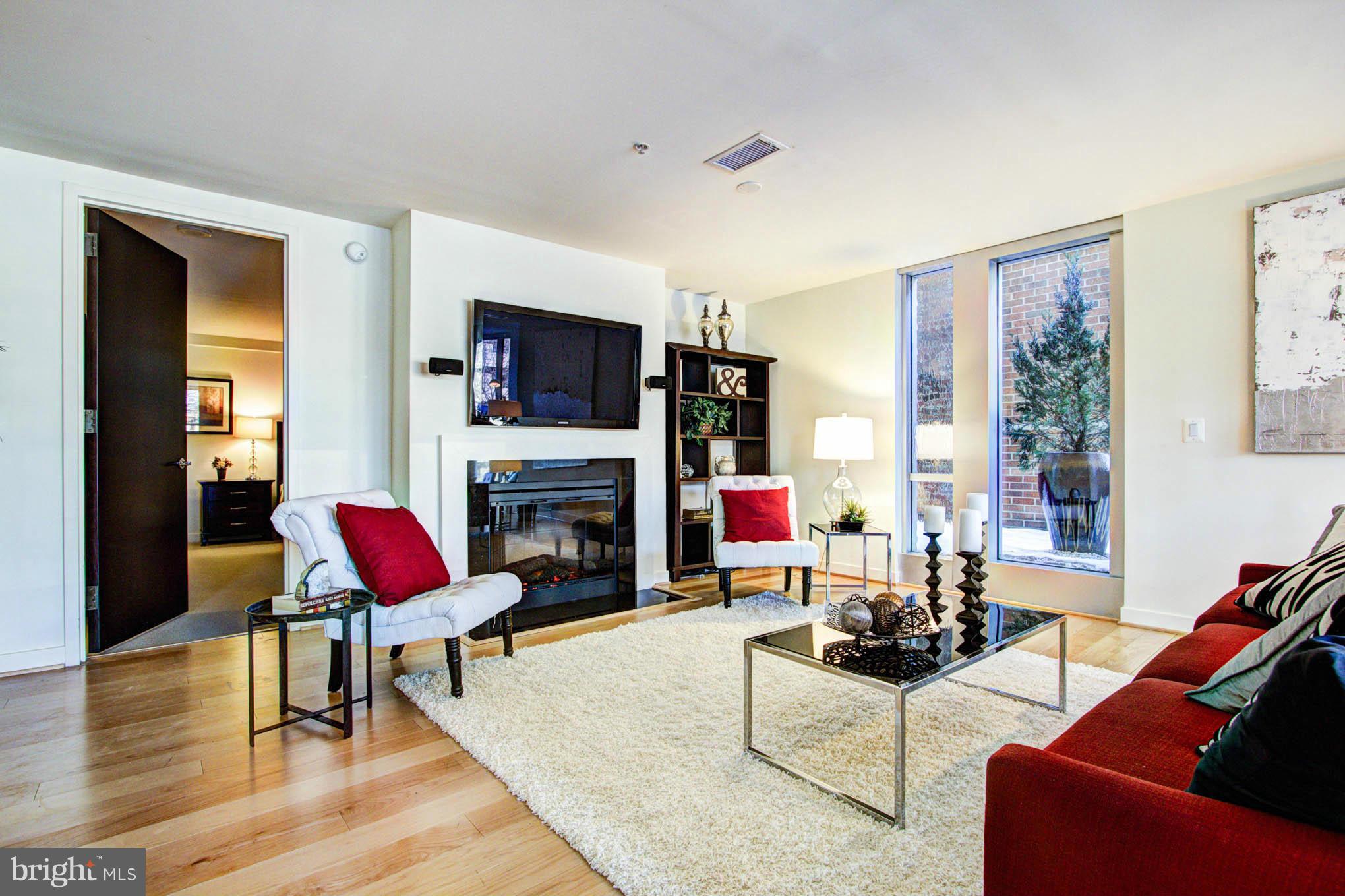 12025 New Dominion Parkway, Unit LL103 Reston, VA 20190 - Photo 7 of 30 a living room with furniture a fireplace and a flat screen tv