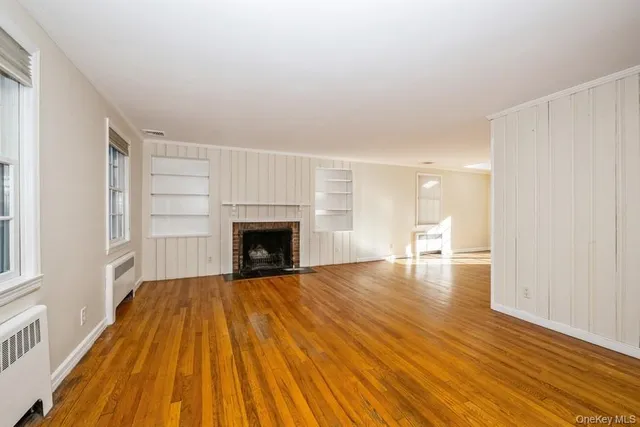 a view of empty room with wooden floor and fireplace