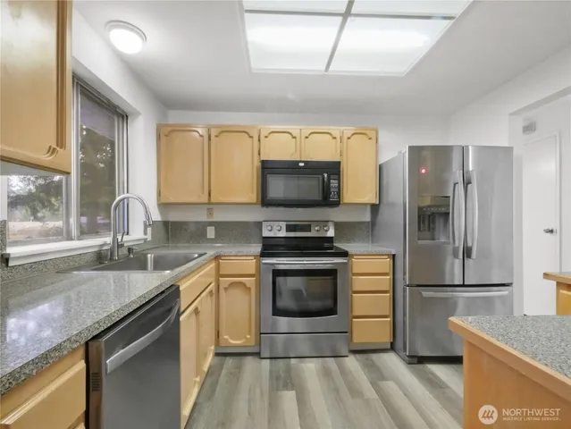 a kitchen with granite countertop a sink stainless steel appliances and counter space