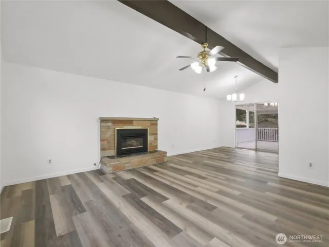 an empty room with chandelier fan and fireplace