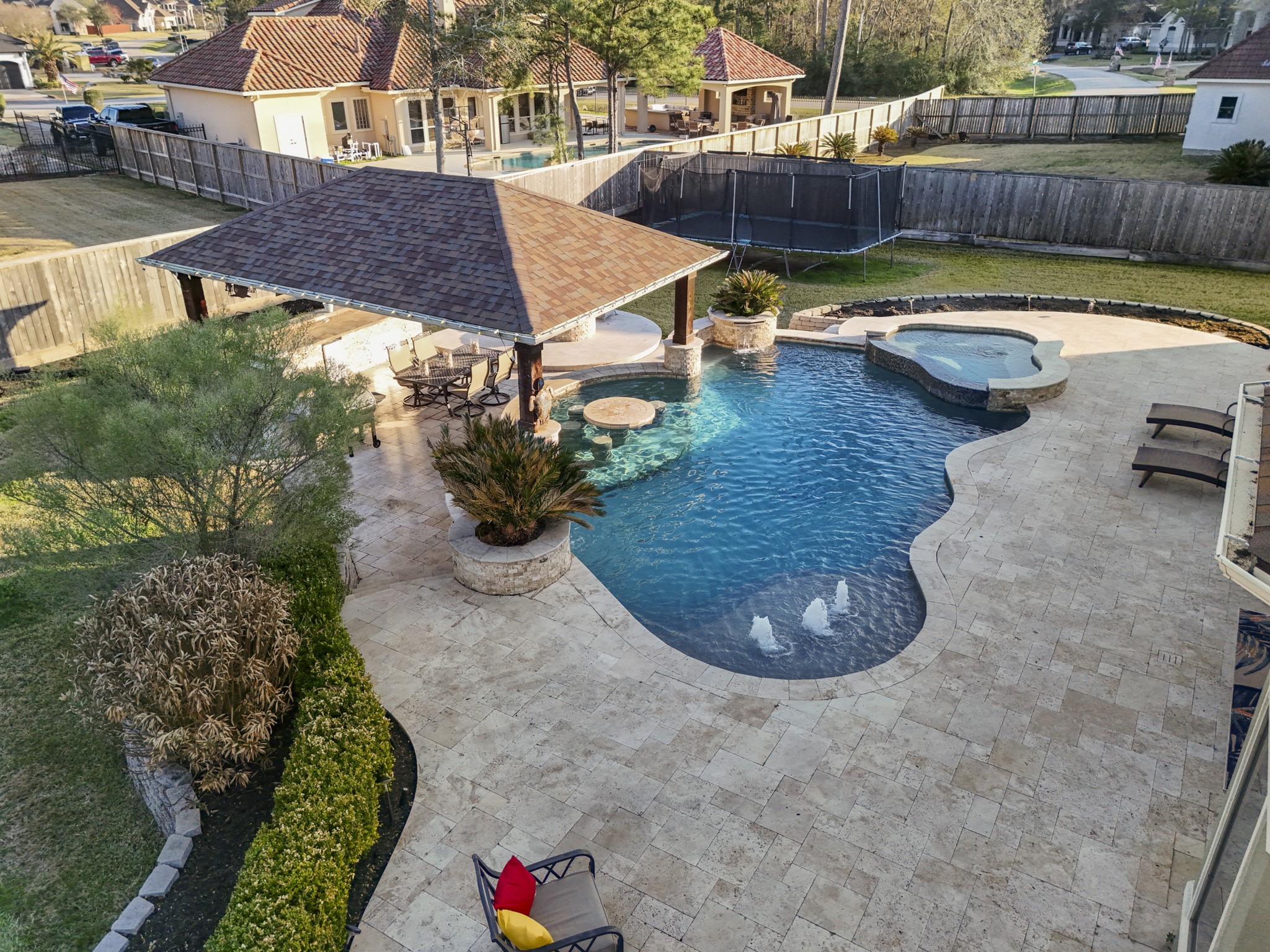 25606 Windy Isle Court Spring, TX 77389 - Photo 5 of 45 The backyard oasis resort style swim-up bar cabana featuring travertine coping and decking around the pool, raised spa with mosaic tile overflow, gorgeous fountains and in pool seating, multilevel outdoor kitchen and outdoor covered living area, circular fire pit and still plenty of grass for the children or pets to play.