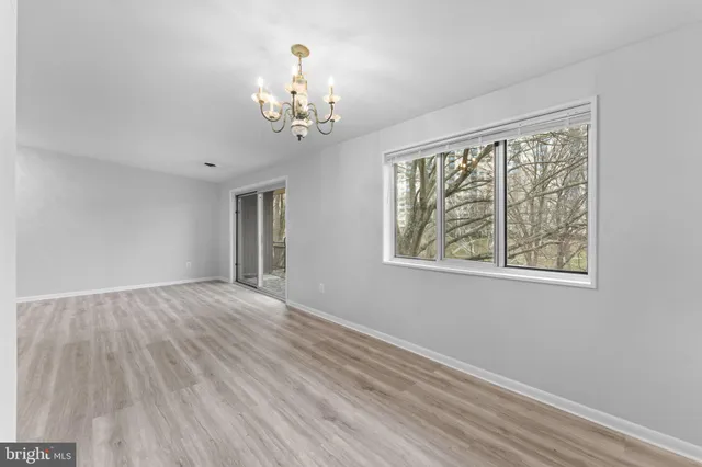 a view of a room with wooden floor chandelier and windows