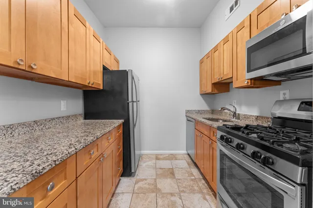 a kitchen with granite countertop a sink a stove and cabinets