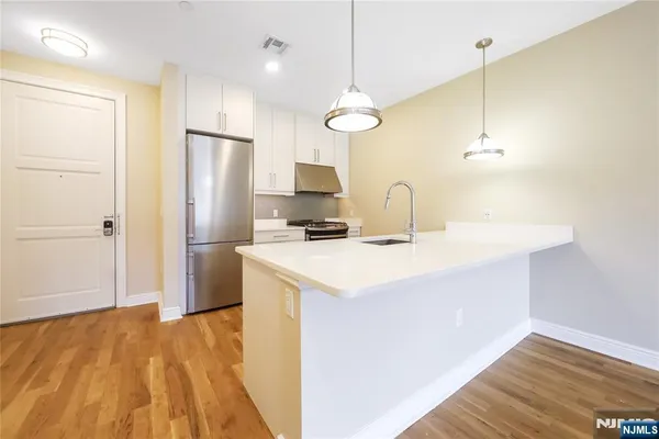 a kitchen with a refrigerator a sink and a wooden floor