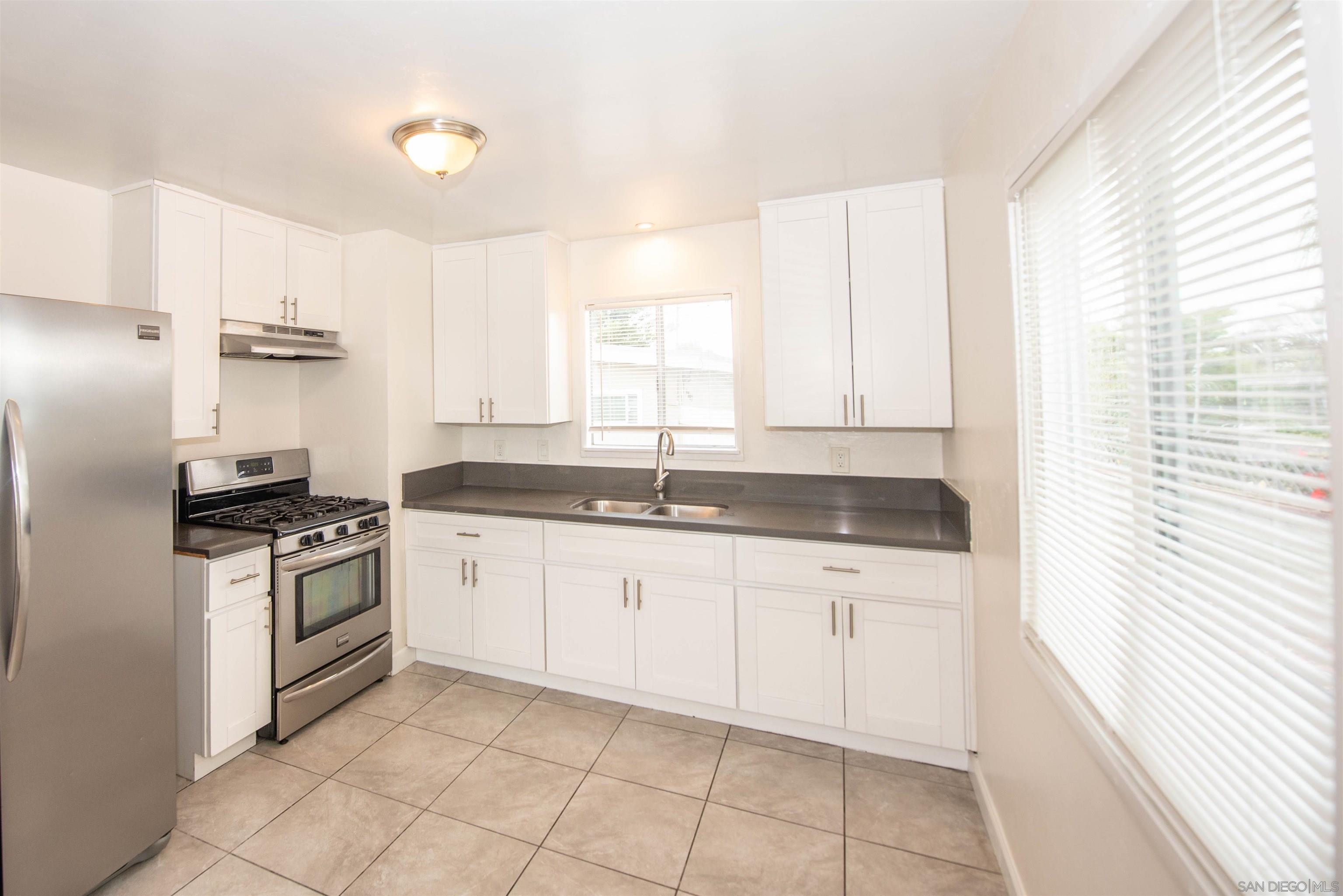 a kitchen with granite countertop white cabinets white appliances a sink and a window