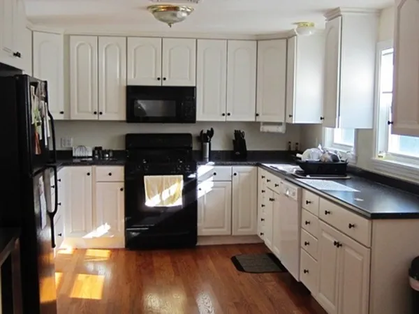 a kitchen with granite countertop a refrigerator a sink and wooden cabinets